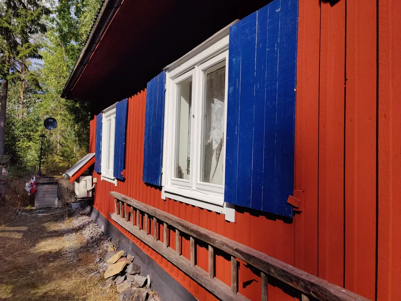 Painting work on a timber facade with white windows and blue shutters